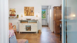 A kitchen with white cabinets, a wooden cabinet, and a dining area with a patterned tablecloth.