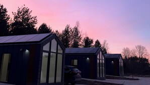 Ein moderner Gebäudekomplex mit großen Fenstern und Solaranlagen vor einem Dämmerhimmel.