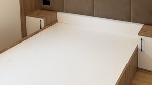 Ein Schlafzimmer mit einem hölzernen Kopfteil, einem weißen Bett und einem kleinen Nachttisch.