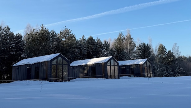 Ein schneebedecktes Feld mit drei Holzhütten.