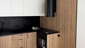 Eine moderne Küche mit Holzschränken, einer schwarzen Arbeitsplatte und einem eingebauten Ofen.