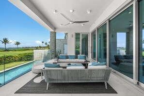 A modern outdoor living area with a pool, a sofa set, and a ceiling fan. - Exclusive 4 Bedroom Four Seasons Resort, Private Pool & Hot Tub, Steps to Beach (Rio Grande)