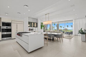 A modern kitchen with a central island, built-in appliances, and a dining area with a view. - Exclusive 4 Bedroom Four Seasons Resort, Private Pool & Hot Tub, Steps to Beach (Rio Grande)