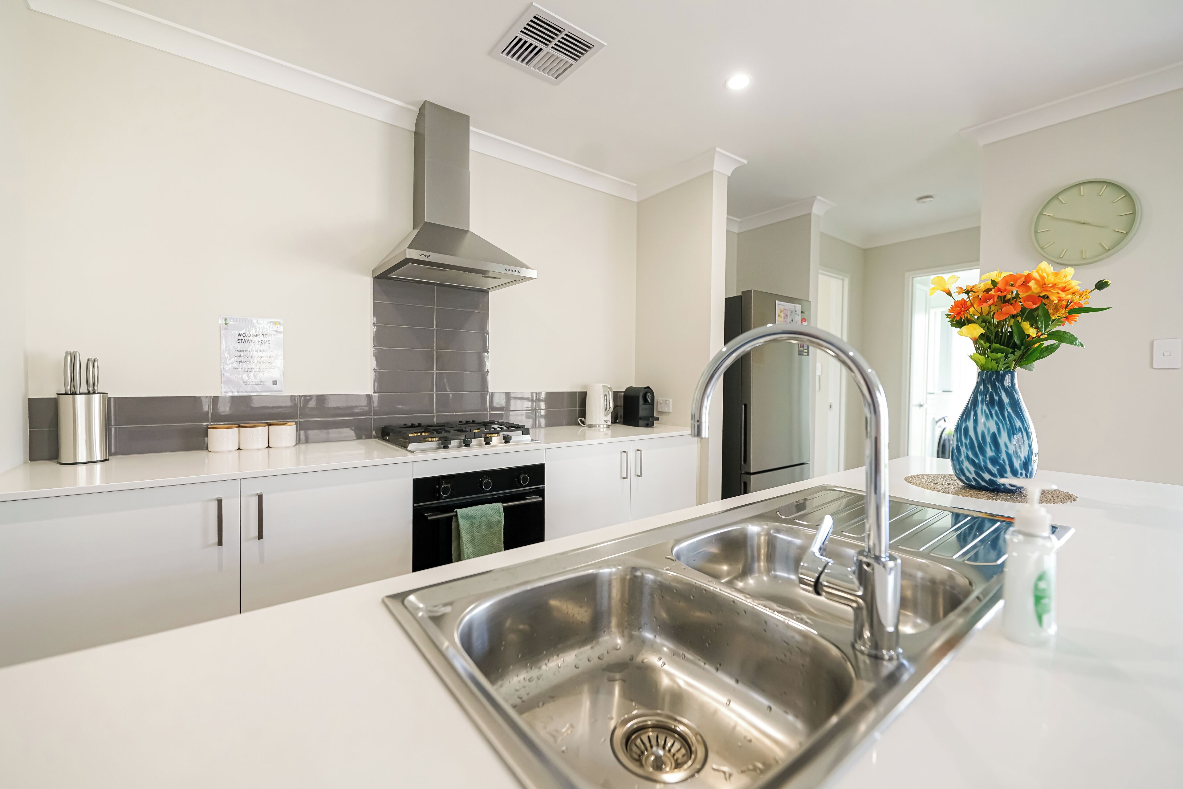 A modern kitchen with stainless steel appliances, a white countertop, and a vase with flowers.