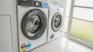Dues rentadores amb càrrega frontal en una sala de bugaderia amb vista a una zona enjardinada.