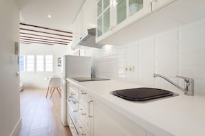 Una cocina moderna con armarios blancos, encimera negra y pileta de acero inoxidable.