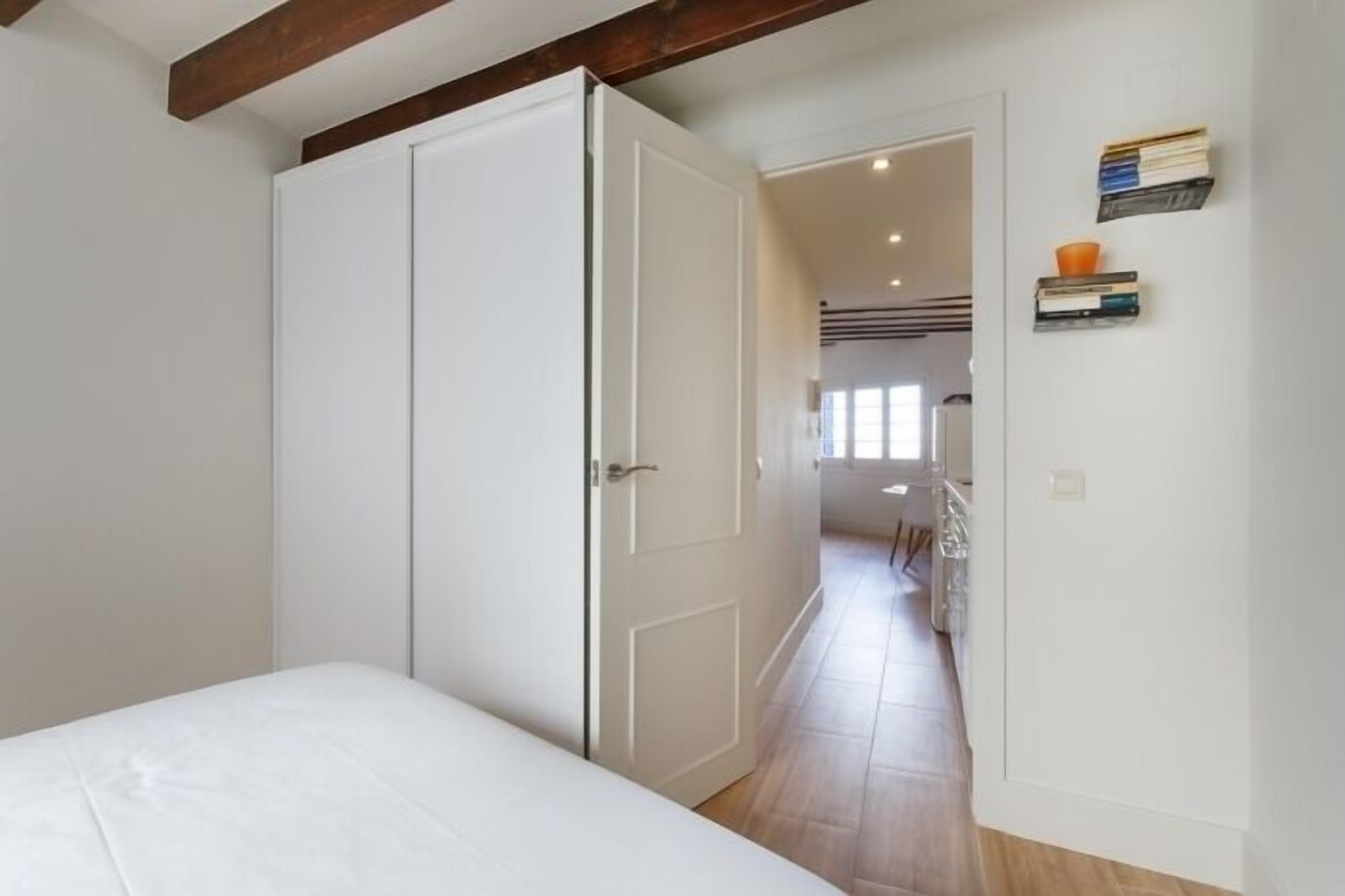 Een slaapkamer met een bed, een kast en een deur naar een gang.