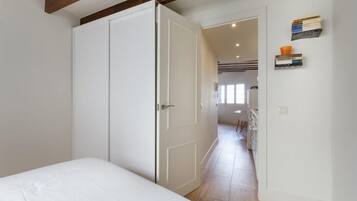 Een slaapkamer met een bed, een kast en een deur naar een gang.