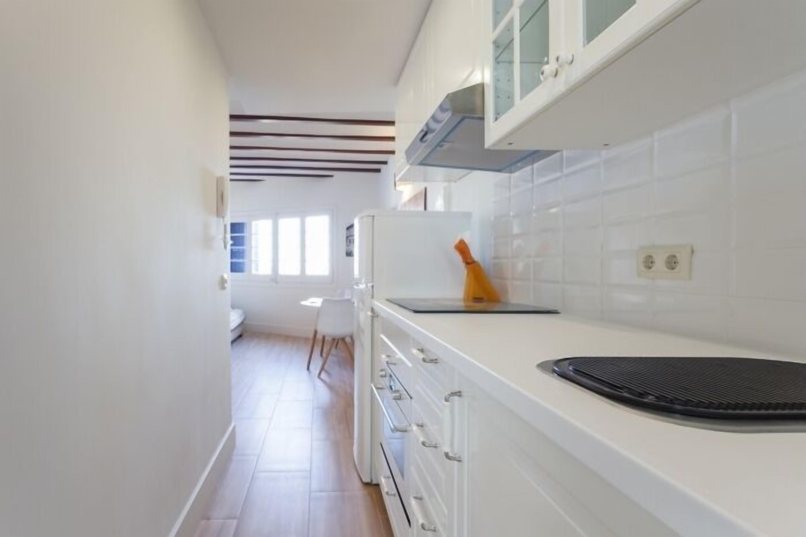 A kitchen with white cabinets, a countertop, and a black appliance.