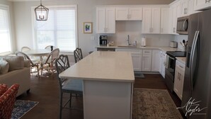 Een moderne keuken met witte kasten, een centraal eiland en roestvrijstalen apparatuur.