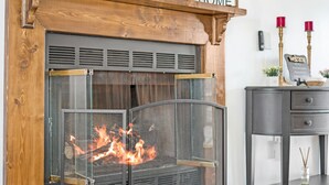 Une cheminée avec un paravent en métal, une cheminée en bois et une pancarte indiquant « Bienvenue ».