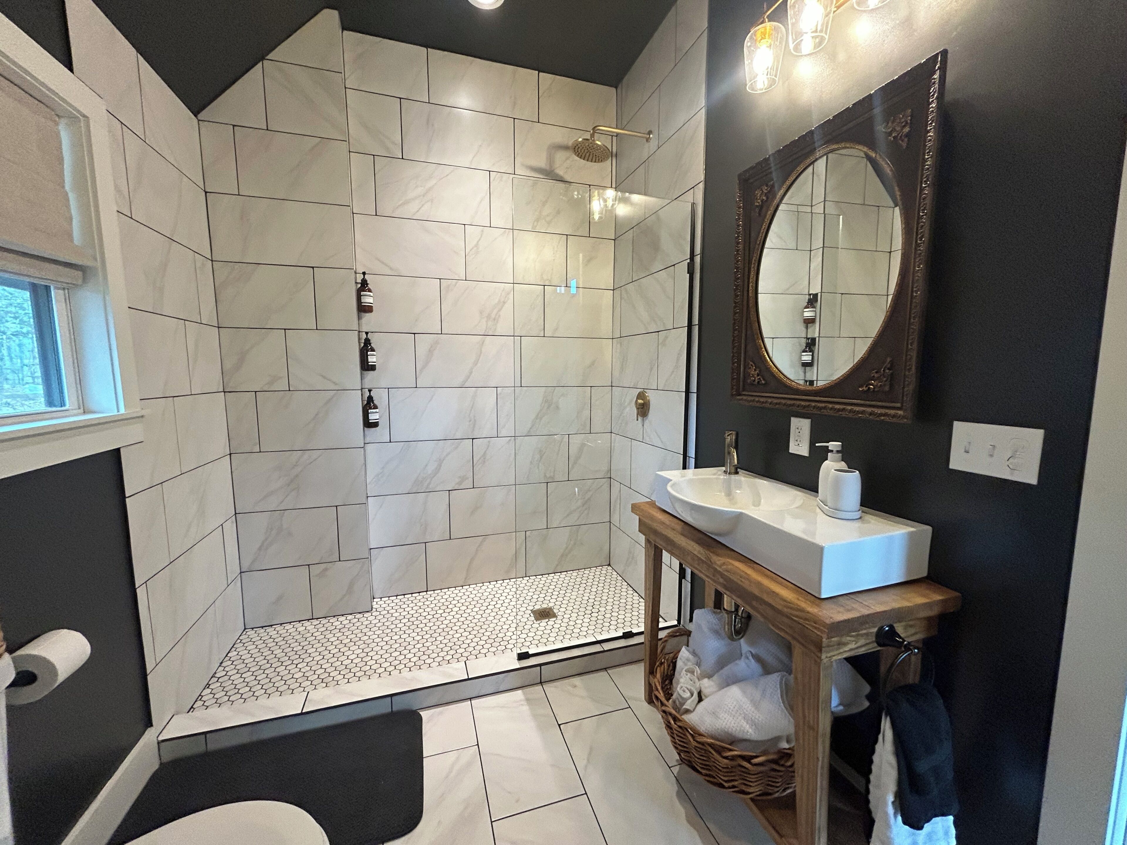 Ein Badezimmer mit Dusche, Waschbecken, Spiegel und Fenster.
