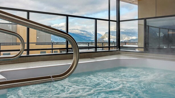 Ett bubbelbad med utsikt över snöklädda berg genom stora fönster.