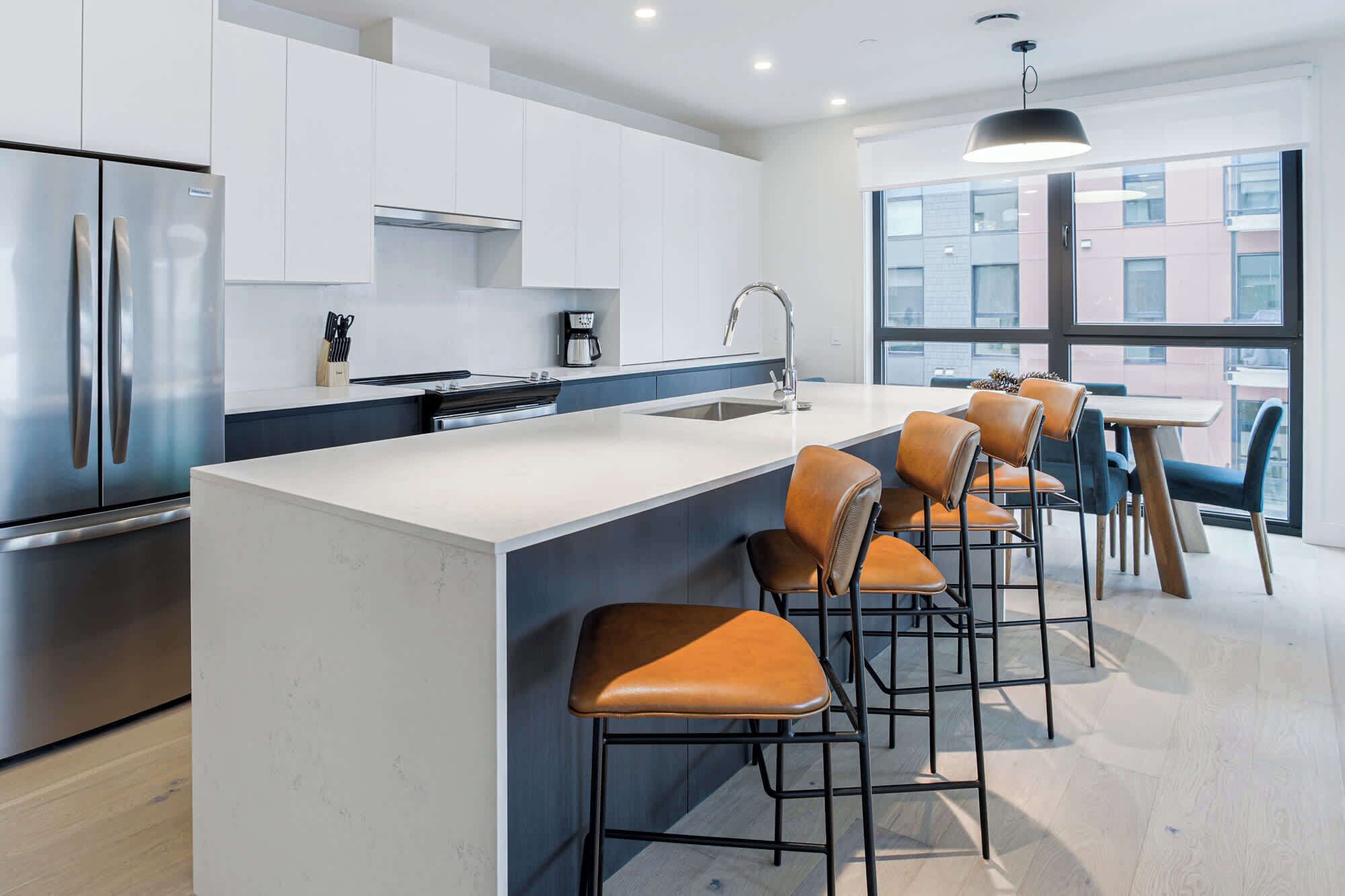 A modern kitchen with a large island, stainless steel appliances, and a view of the city through large windows.