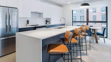 A modern kitchen with a large island, stainless steel appliances, and a view of the city through large windows.