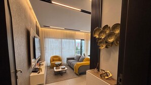 Una sala de estar moderna con un sofá, sillones, una mesa de centro y un televisor.