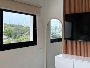 Una habitación con un ventanal grande, un espejo y un televisor de pantalla plana.