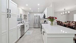 A modern kitchen with white cabinetry, stainless steel appliances, and a central island. - Sarasota Springs Pool Retreat | Heated Pool • Pet-Friendly • Near Siesta Key (Sarasota)