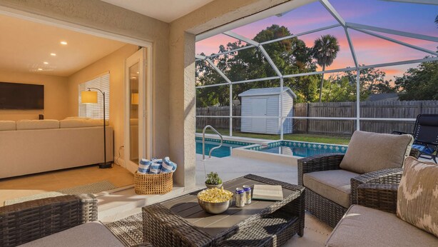A patio area with wicker furniture, a pool, and a view of the backyard. - Sarasota Springs Pool Retreat | Heated Pool • Pet-Friendly • Near Siesta Key (Sarasota)