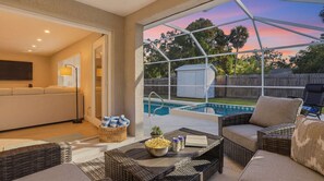 A patio area with wicker furniture, a pool, and a view of the backyard. - Sarasota Springs Pool Retreat | Heated Pool • Pet-Friendly • Near Siesta Key (Sarasota)