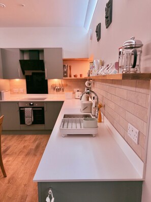 Eine moderne Küche mit weißer Arbeitsplatte, Spüle und Kaffeemaschine.