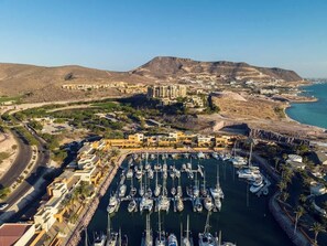 An aerial view of a marina with numerous boats docked, surrounded by residential buildings and a hilly landscape in the background. - Marina View Suite · Beach Club · Housekeeping (La Paz)