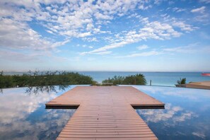An infinity pool with a wooden deck and a view of the ocean. - Vistamar Suite | Family Friendly in Puerta Cortes (La Paz)