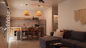 Una cocina moderna con armarios de madera, un comedor con mesa y sillas, y una sala de estar con sofá y mesa de centro.