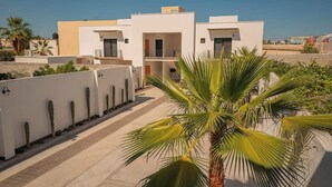 Un edificio residencial moderno con techo plano, paredes exteriores blancas y un patio central con palmeras.