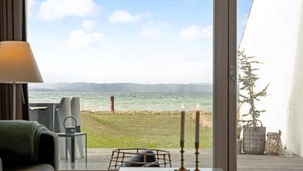 Une chambre avec vue sur un lac, une table éclairée à la bougie et une lampe.