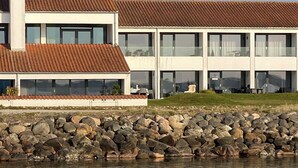 Un bâtiment moderne doté d’un toit en tuiles et de grandes fenêtres, situé à proximité d’une côte rocheuse.