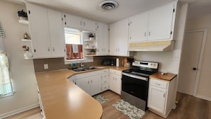 A modern kitchen with white cabinets, a stainless steel stove, and a wooden countertop. - The Brenham Abode is pet friendly and conveniently located close to downtown. (Brenham)