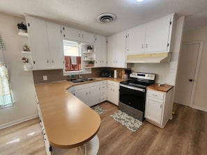 A modern kitchen with white cabinets, a stainless steel stove, and a wooden countertop.