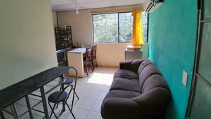 A small, well-lit room with a kitchenette, a sofa, and a dining table. - Beach apartment kilometer 59 (Rural area-Surf city). (La Libertad Department)