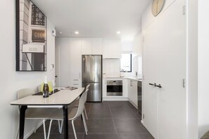 Eine moderne Küche mit weißen Schränken, einem Edelstahl-Kühlschrank und einem Essbereich mit Tisch und Stühlen.