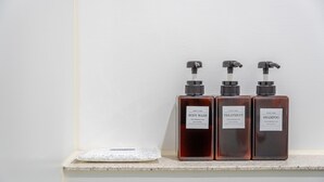 Tres ampolles de gel de dutxa, tractament i xampú sobre una estant.