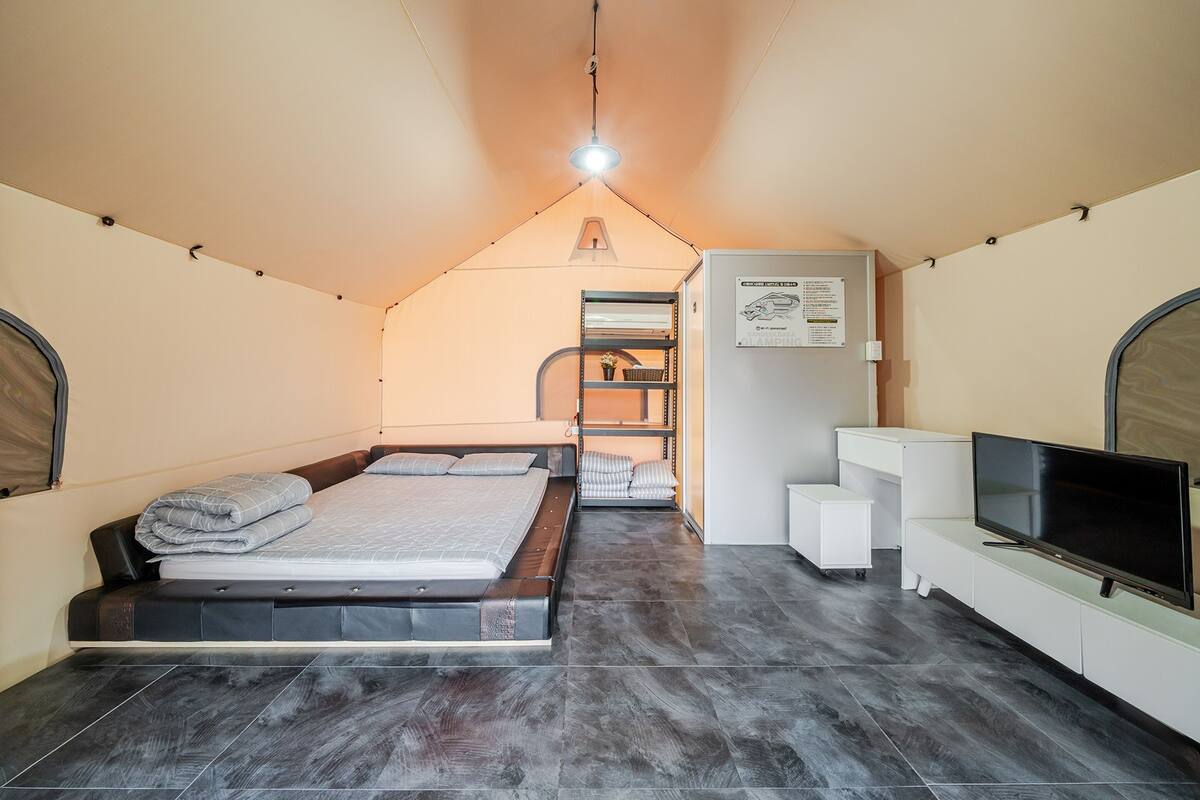 A compact bedroom with a bed, a TV, and a small white cabinet.