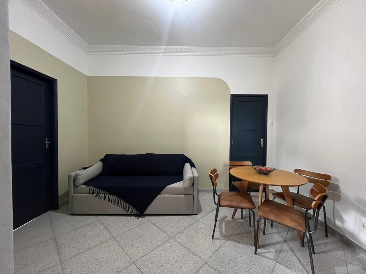 A room with a sofa, a dining table with chairs, and a door.