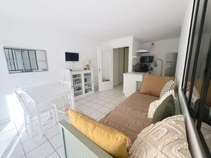 A compact hotel room with a balcony, a bed with patterned bedding, a small kitchenette, and a dining area with a table and chairs. - PORNICHET PLACE DU MARCHE (PORNICHET)