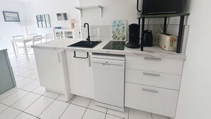 Pieni, käytännöllinen keittiö, jossa on pesuallas, kahvinkeitin, leivänpaahdin ja mikroaaltouuni työtasolla.