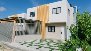 Een modern huis met twee verdiepingen, een witte gevel, een houten omheining en een gazon.