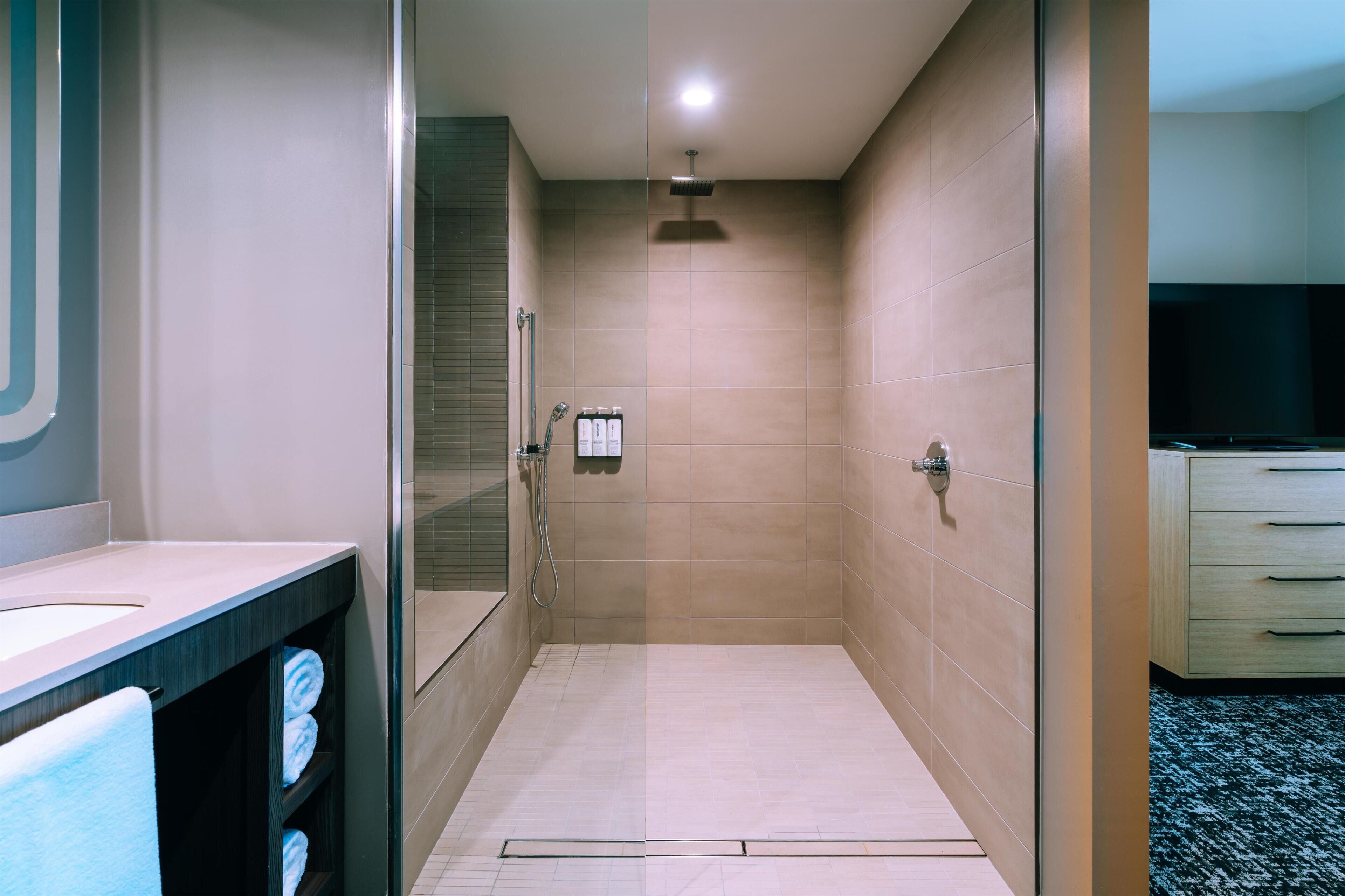 Un baño moderno con cabina de ducha de vidrio, tocador con espejo y inodoro.