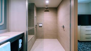 Un baño moderno con cabina de ducha de vidrio, tocador con espejo y inodoro.