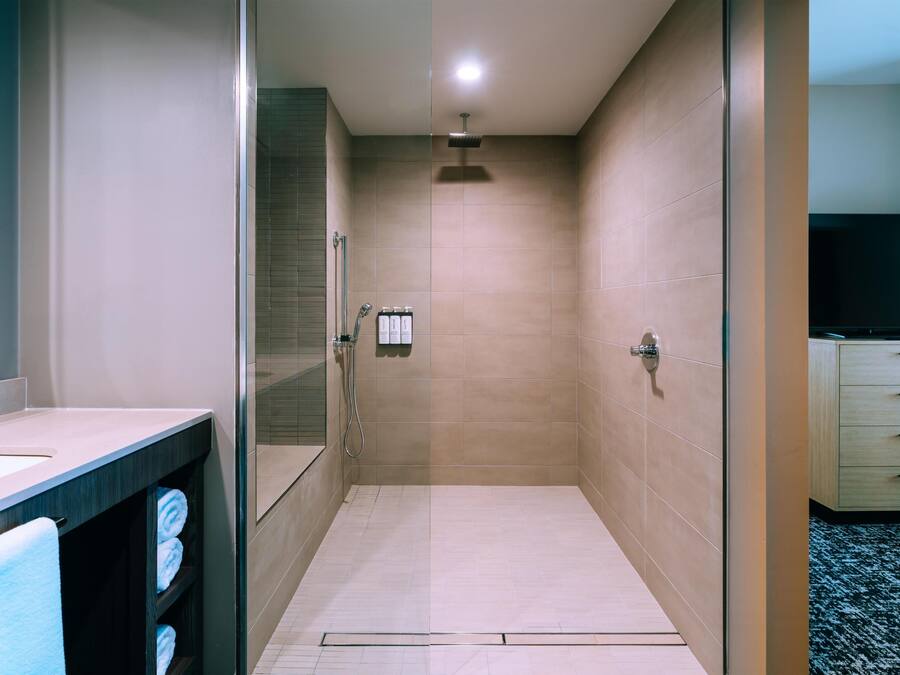 Un baño moderno con cabina de ducha de vidrio, tocador con espejo y inodoro.