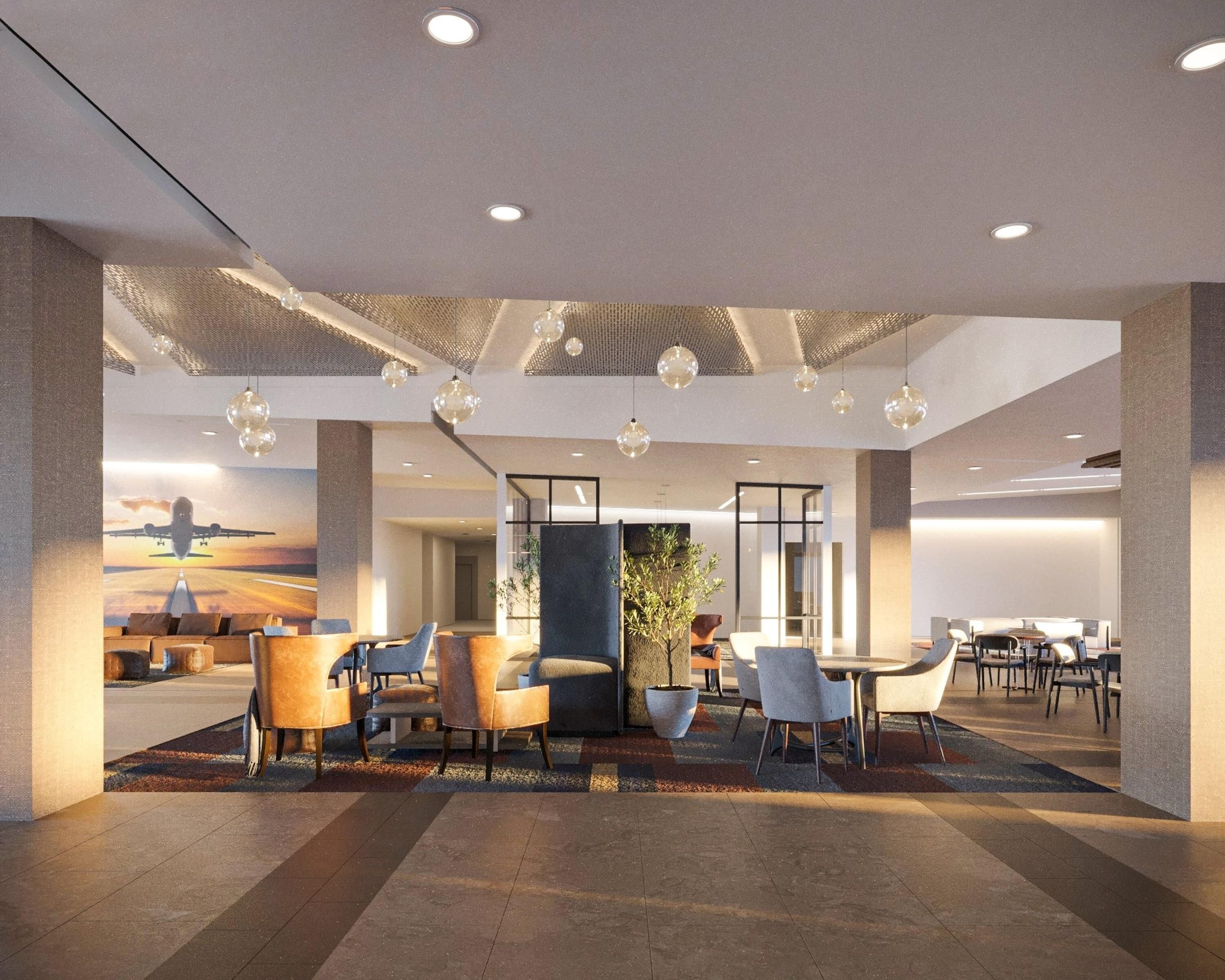 A modern hotel lobby with a seating area, a large plant, and a mural of an airplane on the wall.