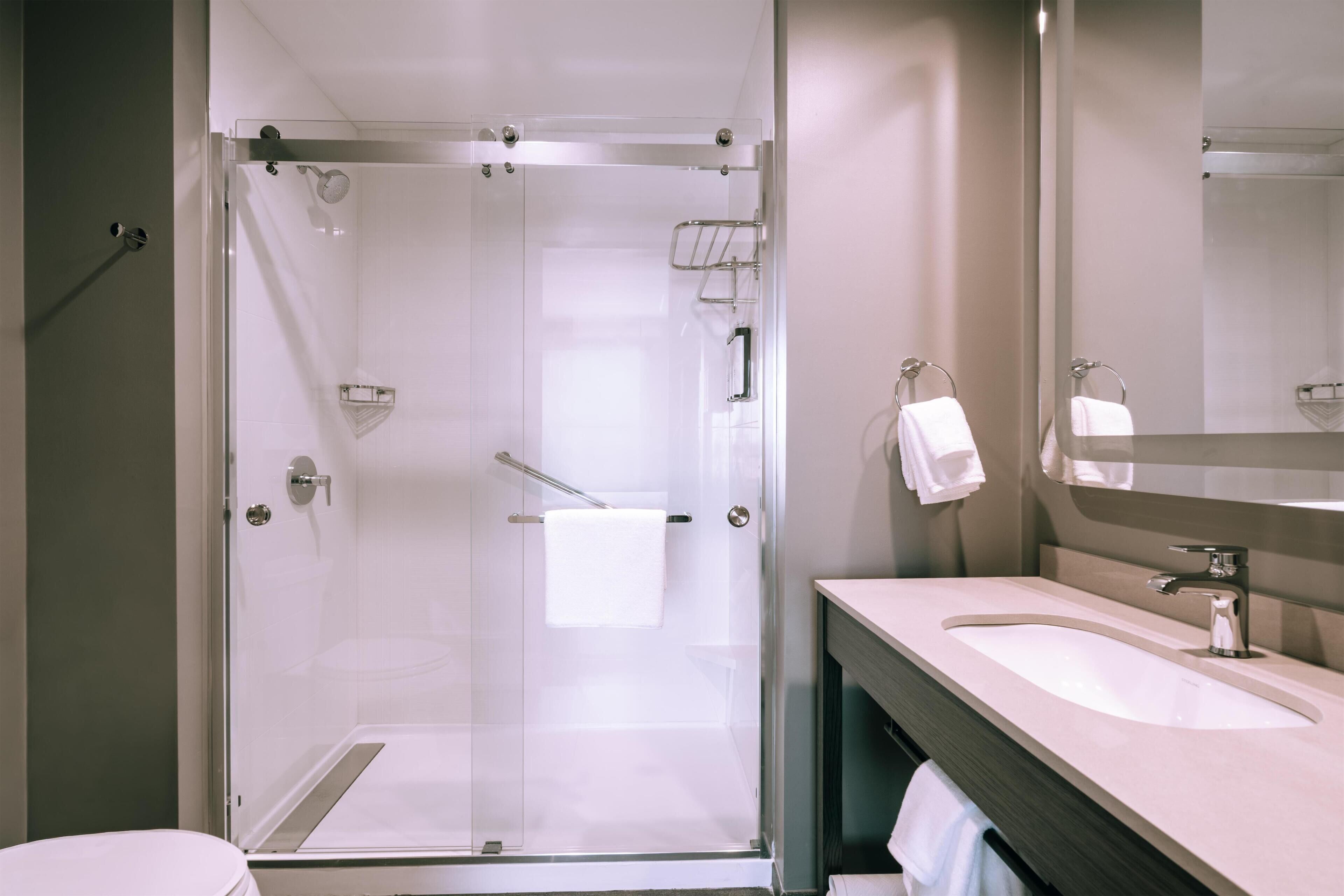 A modern bathroom with a glass-enclosed shower, a sink, and a mirror.