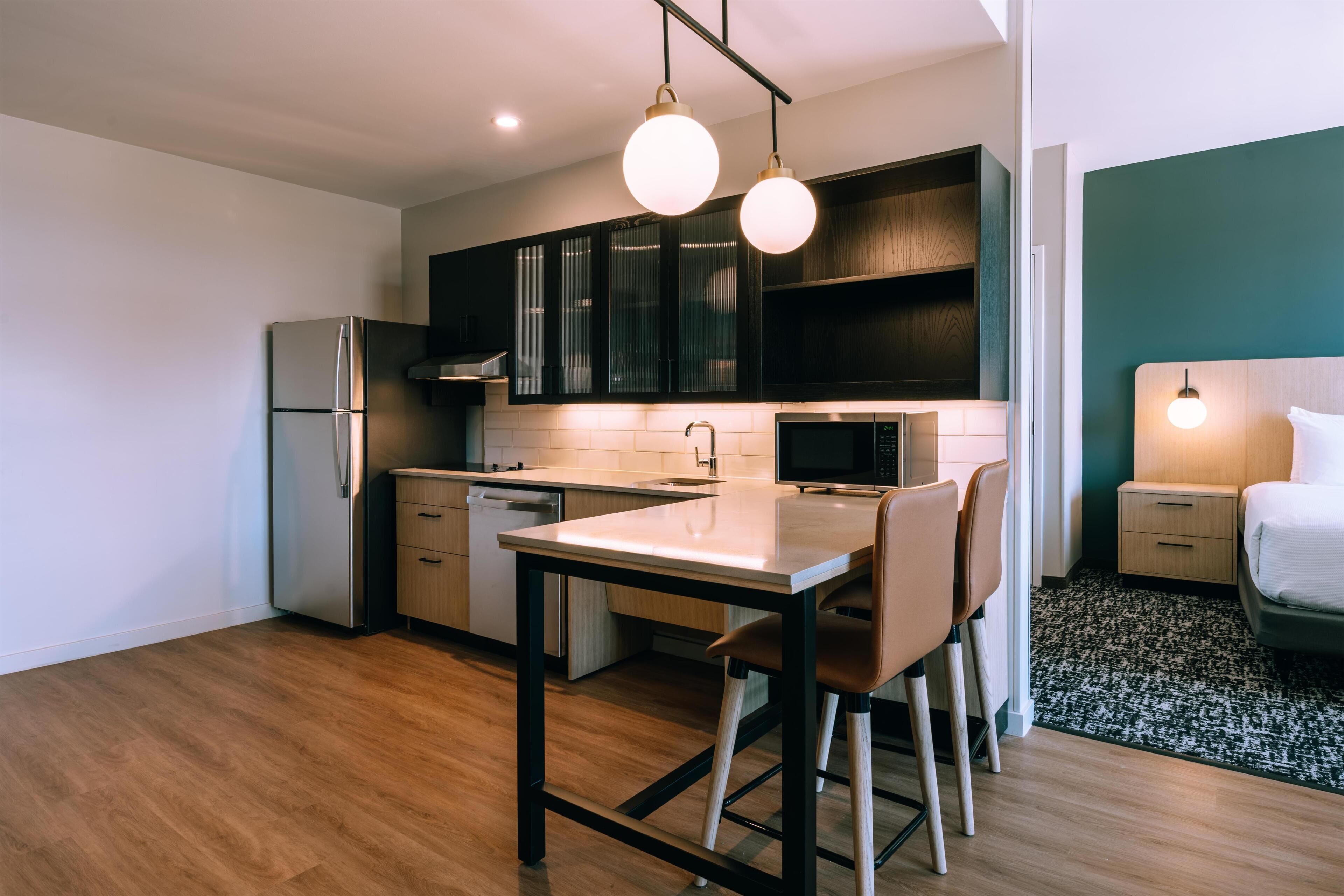 Una cocina moderna con refrigerador, microondas y armarios de madera.