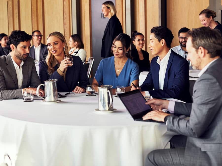 A conference room with round tables, laptops, and water pitchers.