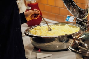 A buffet with a large metal bowl of mashed potatoes.