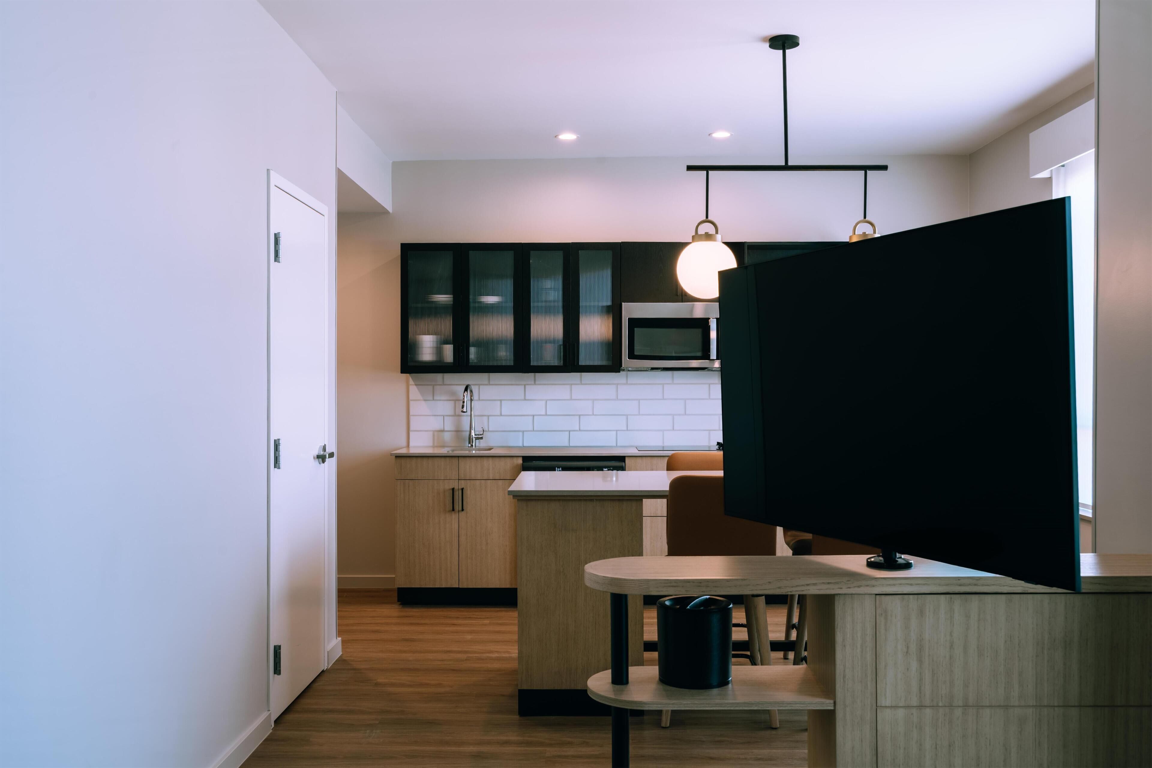 Una cocina moderna con microondas, armarios y una zona de comedor con mesa y sillas.